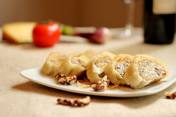 White plate with sliced mushroom strudel. Beige surface.