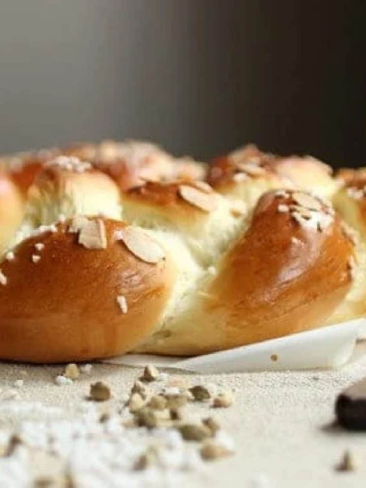 Braided pulla bread on cream colored cloth with cardamom pods.