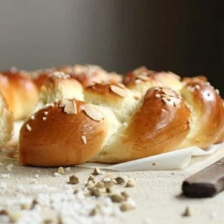 Braided pulla bread on cream colored cloth with cardamom pods.