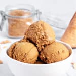 Three scoops of brown sugar ice cream in a white bowl. Gray background, brown sugar jar.