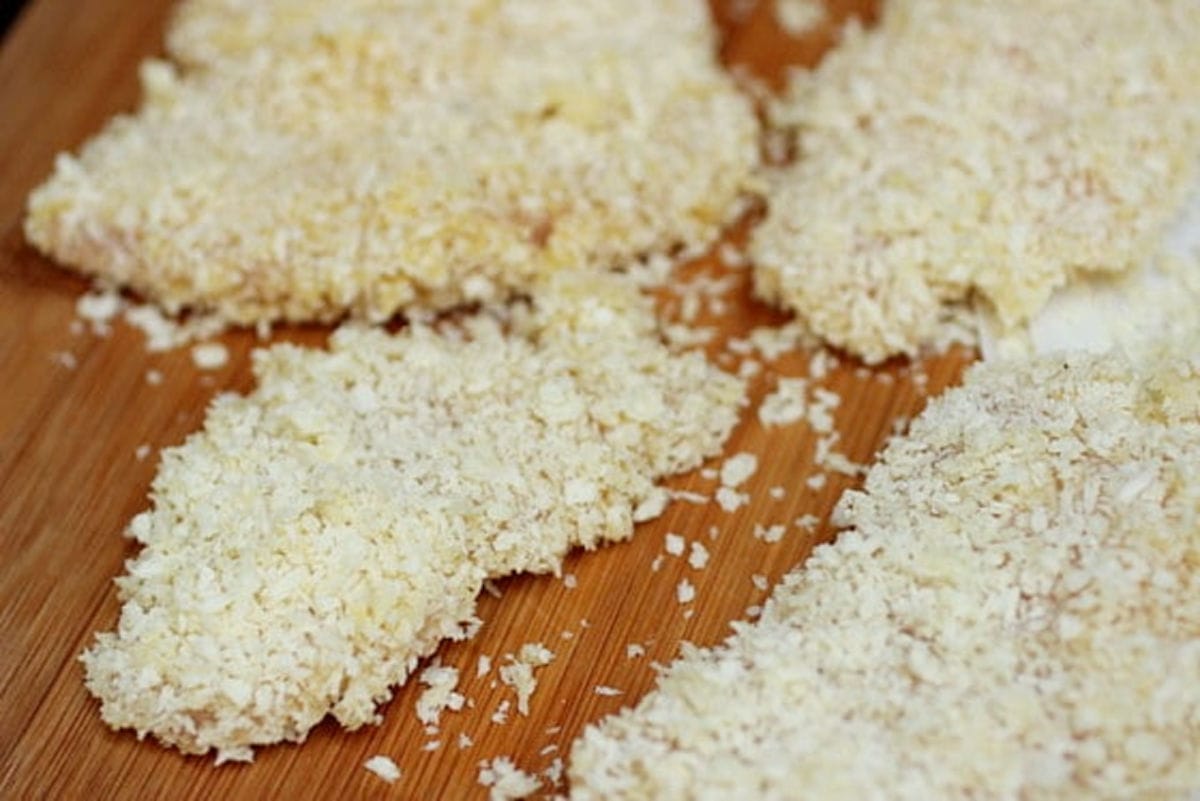 Breaded chicken tenders on a bamboo wooden board.