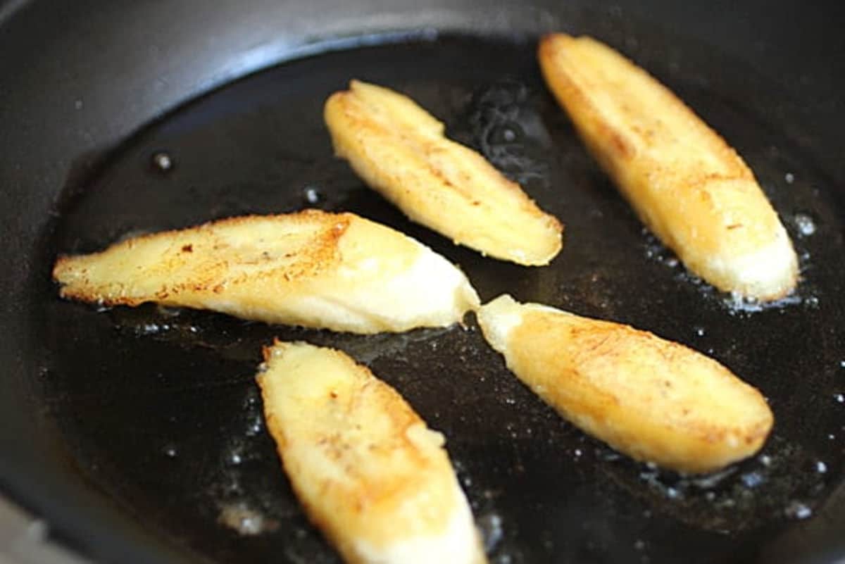 Fried banana pieces in a black skillet.