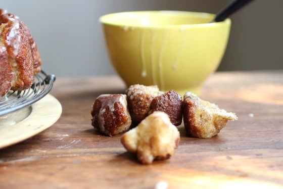 Monkey bread pieces on a wooden table, yellow bowl in background. 