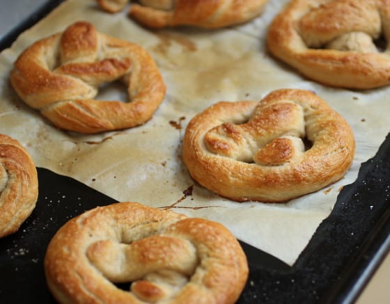 Baked soft Pretzels still on baking tray with parchment paper.