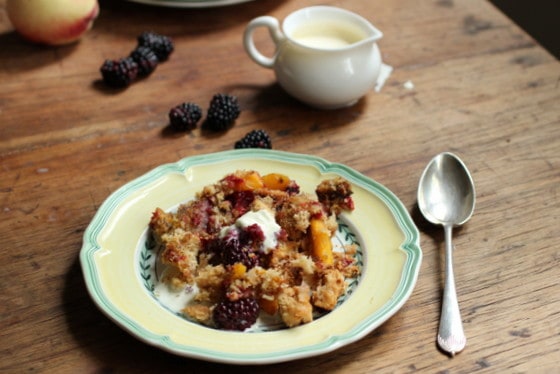 Yellow plate with brown berry on a wooden table. A silver spoon and cream jar. 