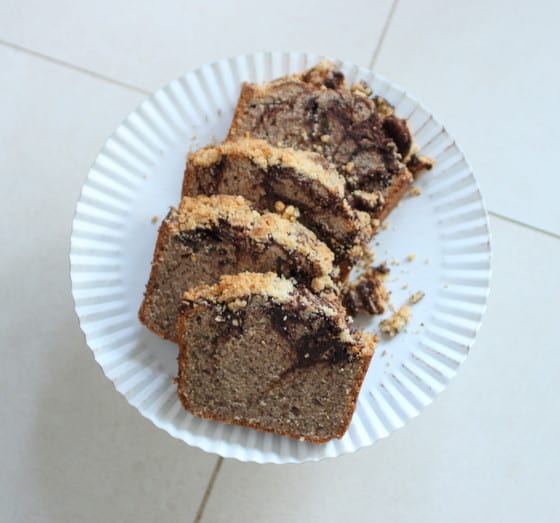 Chocolate Swirl Walnut Pound Cake on a white cake stand on a white floor.