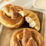 Whole and halved pretzels on a wooden board.
