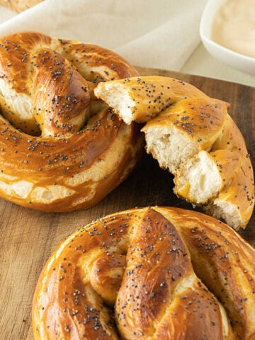 Whole and halved pretzels on a wooden board.