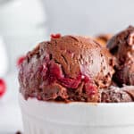 Close up scoop of cherry chocolate ice cream in a white bowl. Gray background.