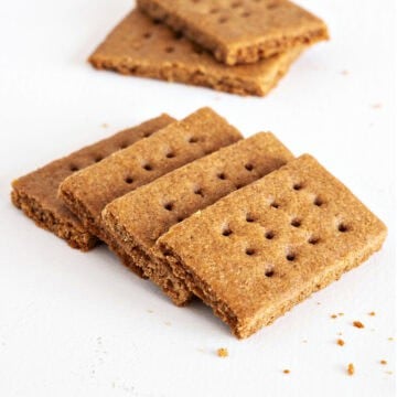 Close up of several homemade graham cracker on a white surface.