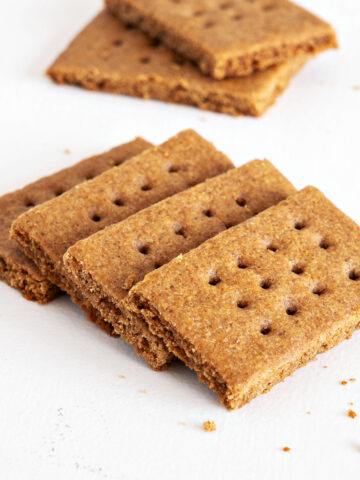 Close up of several homemade graham cracker on a white surface.