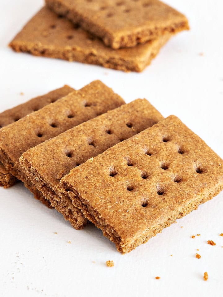 Close up of several homemade graham cracker on a white surface.