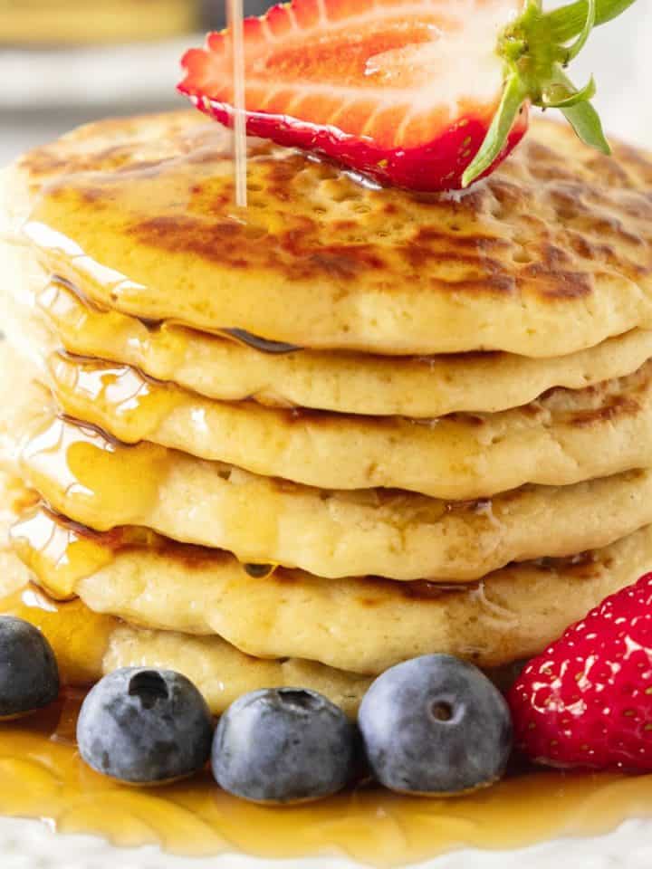 Close up image of pancake stack with fresh berries and syrup.