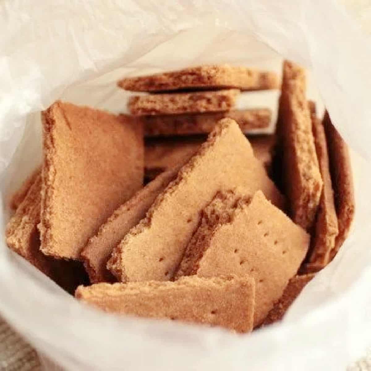 Several pieces of homemade graham crackers in an opened plastic bag. View from the top.
