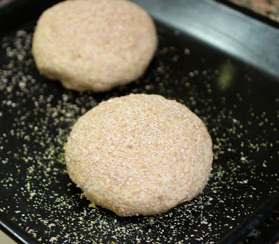 Two rounds of unbaked bread on black oven tray.