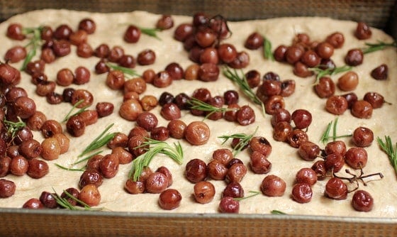Unbaked Focaccia dough topped with Grapes on a metal pan