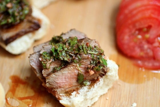 Open Marinated Steak and Chimichurri Slide on wooden table, tomato slices