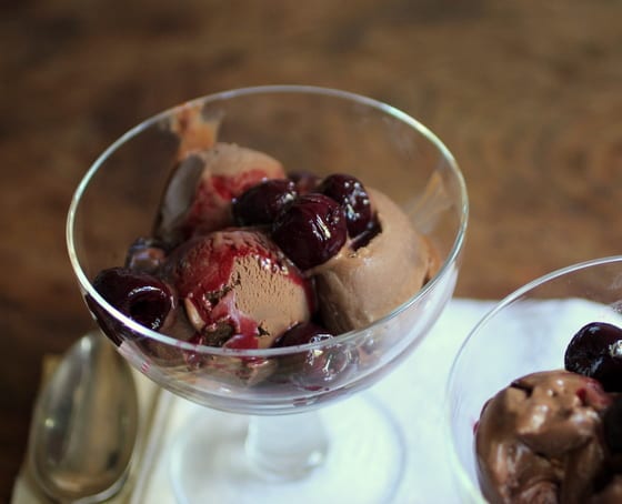 Top view of chocolate ice cream in stem glass on wooden table.