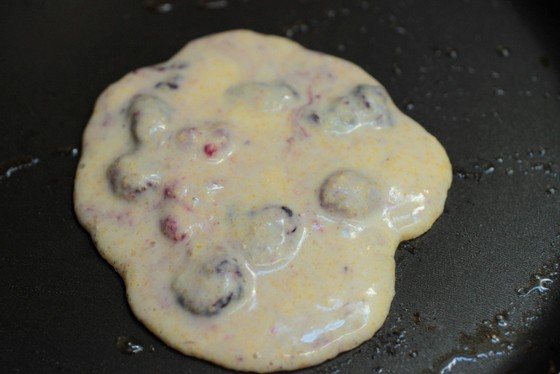 Cornmeal berry pancake batter on black skillet. 