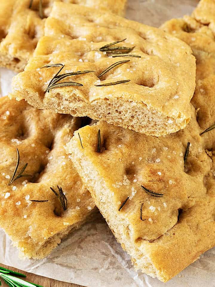 Pieces of whole wheat focaccia in a pile on white paper. Close up image.