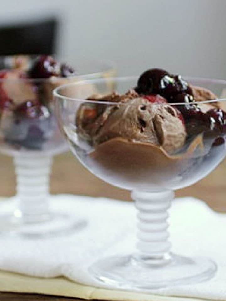 Cherry chocolate ice cream in glass stem wide cups on a white cloth.
