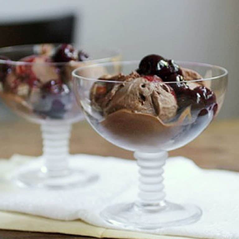 Cherry chocolate ice cream in glass stem wide cups on a white cloth.