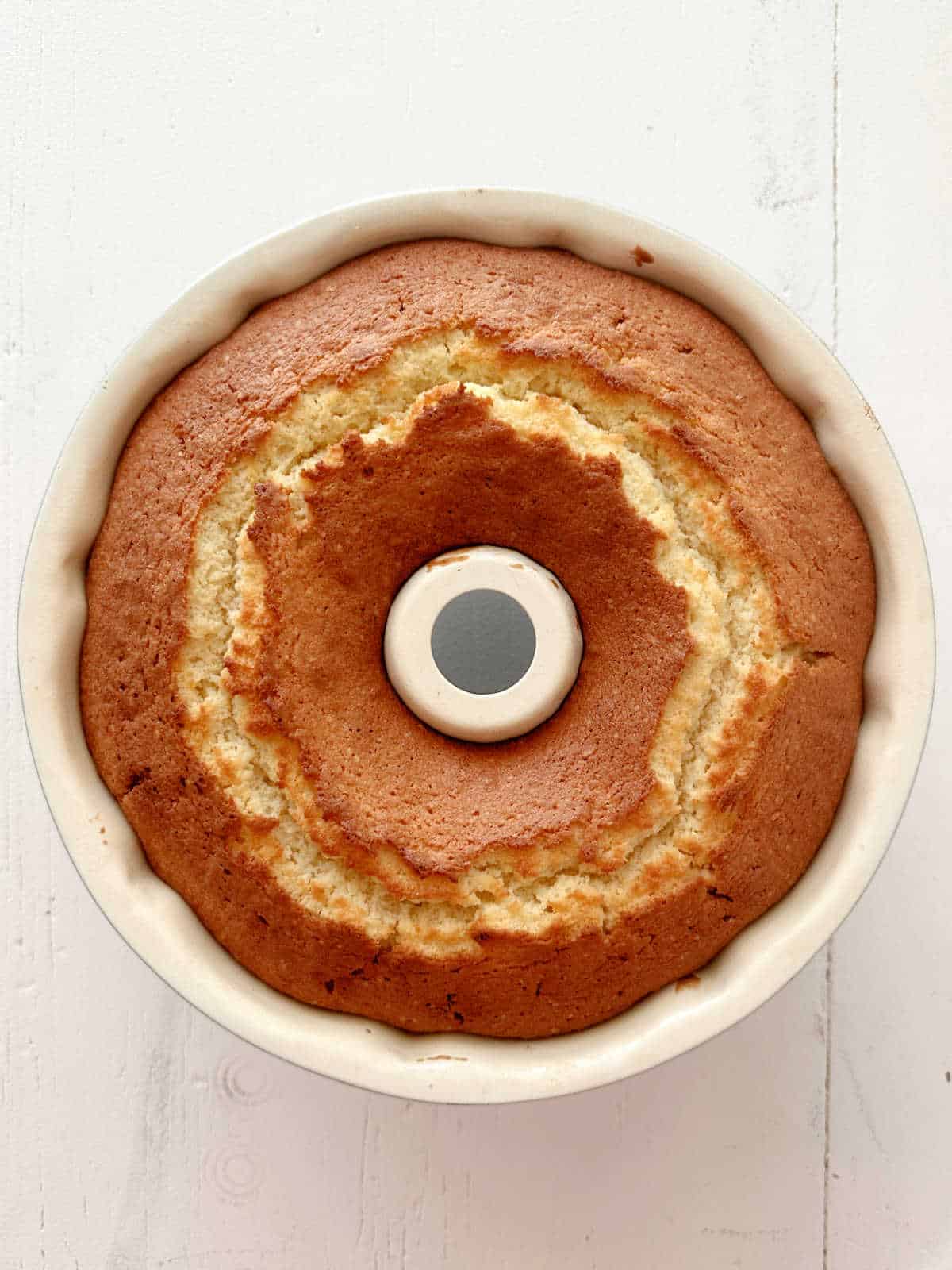 Baked bundt cake in the pan on a white surface. Top view.
