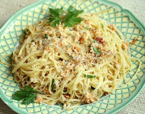 Green and white plate with pile of linguini with cauliflower sauce. 