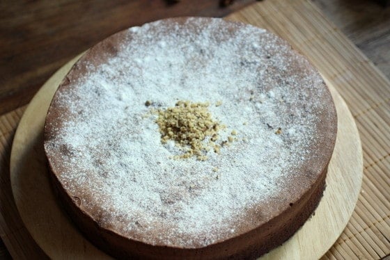 Top view of powdered sugar dusted chocolate cake on wooden plate and placemat. 