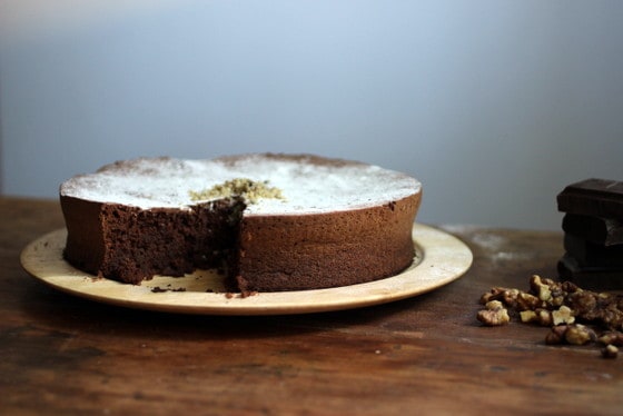 Flourless chocolate cake on a wooden plate on top of a wooden table. 