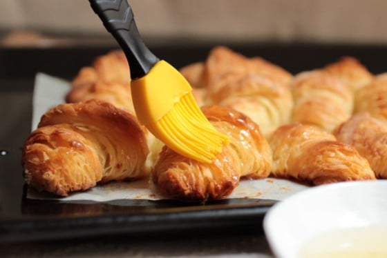 Brushing syrup on croissants with a yellow silicon brush. 