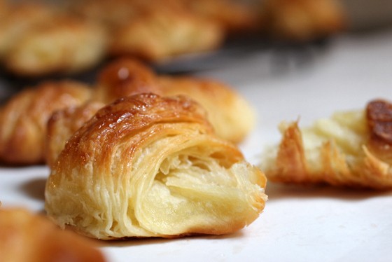 Flaky bitten French croissant on white surface.