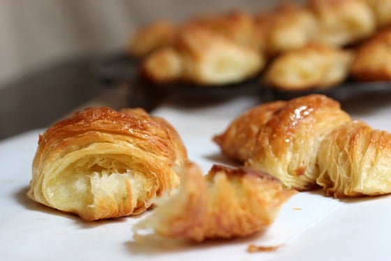 Whole and pieces of croissants on white parchment paper. 
