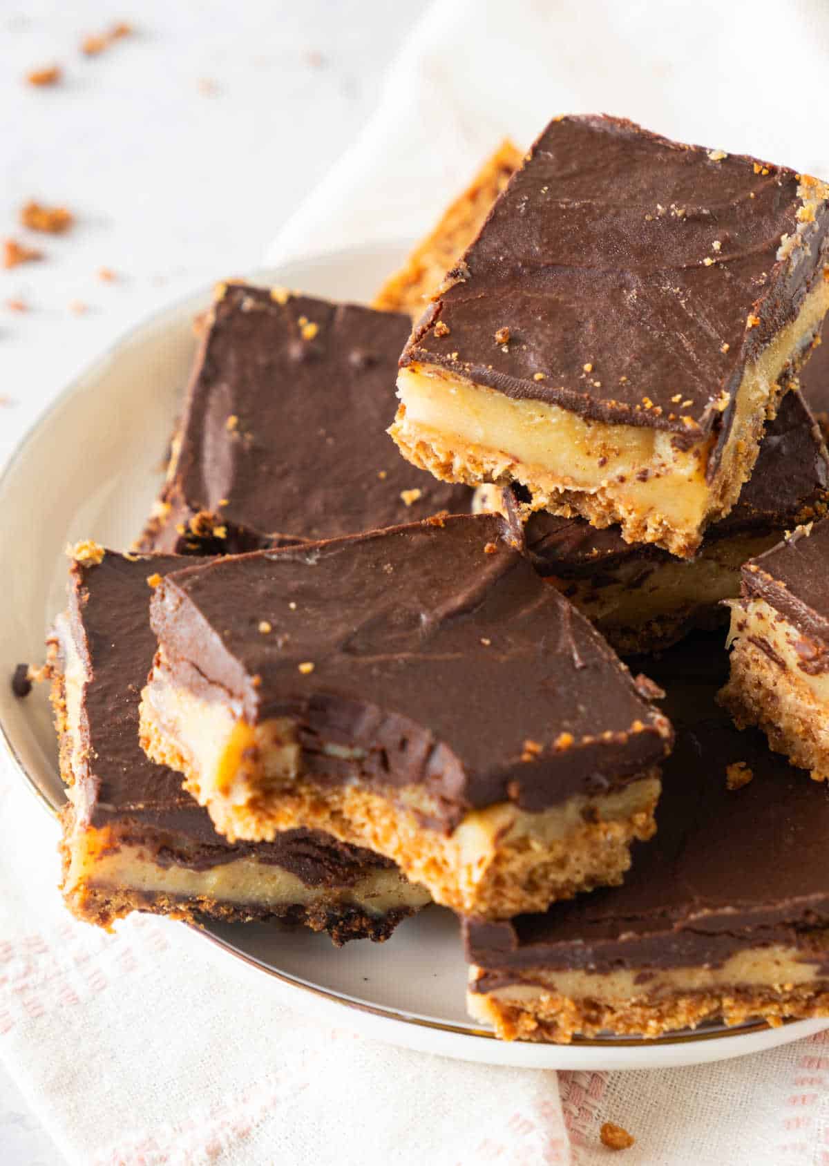 White plate with pile of millionaire bars; one is bitten. White background.