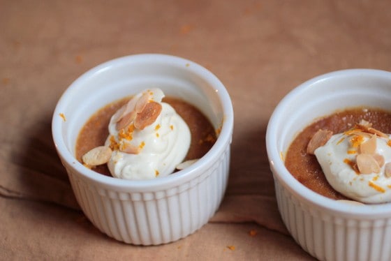 Two white ramekins with white chocolate cream puddings on a beige cloth. 