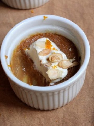 Eaten caramel white chocolate custard with cream on a white ramekin on a brown cloth.