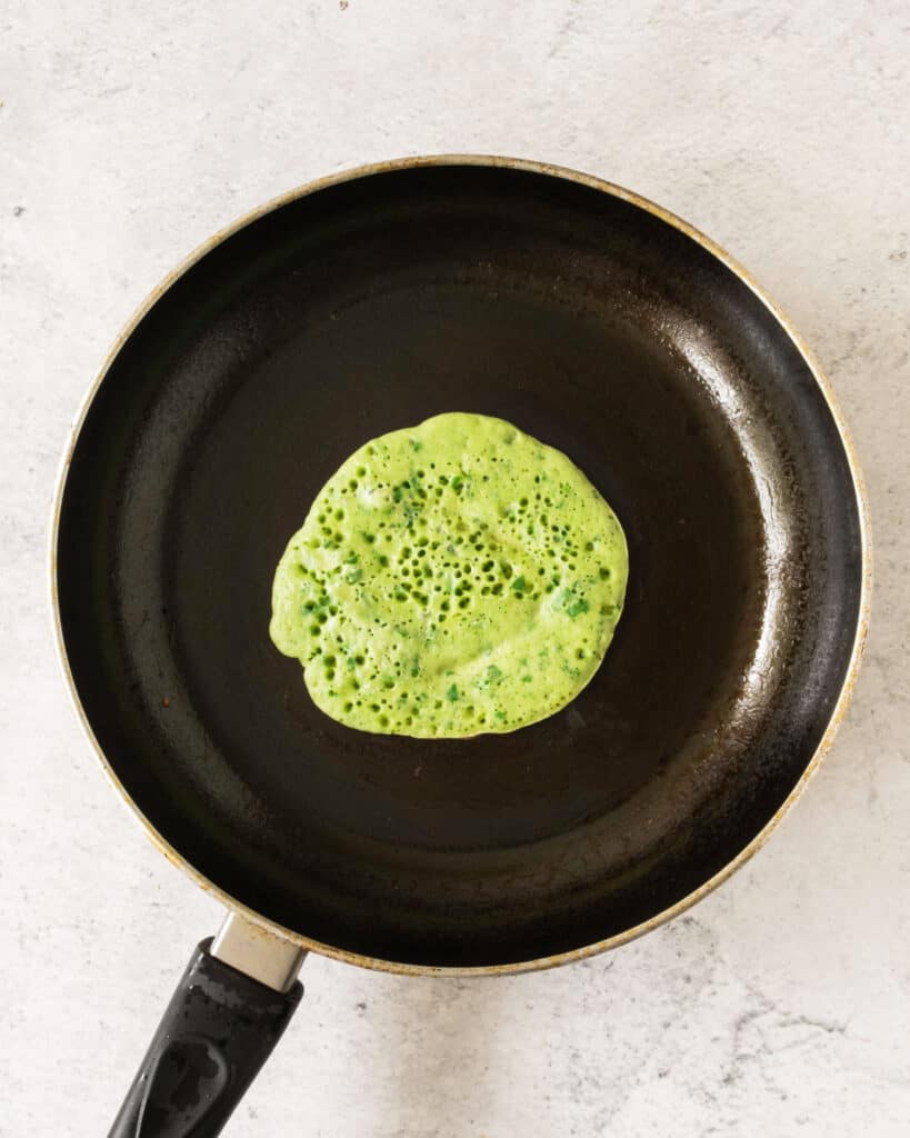 Top view, stone background. Cooking chard pancake on a black skillet.