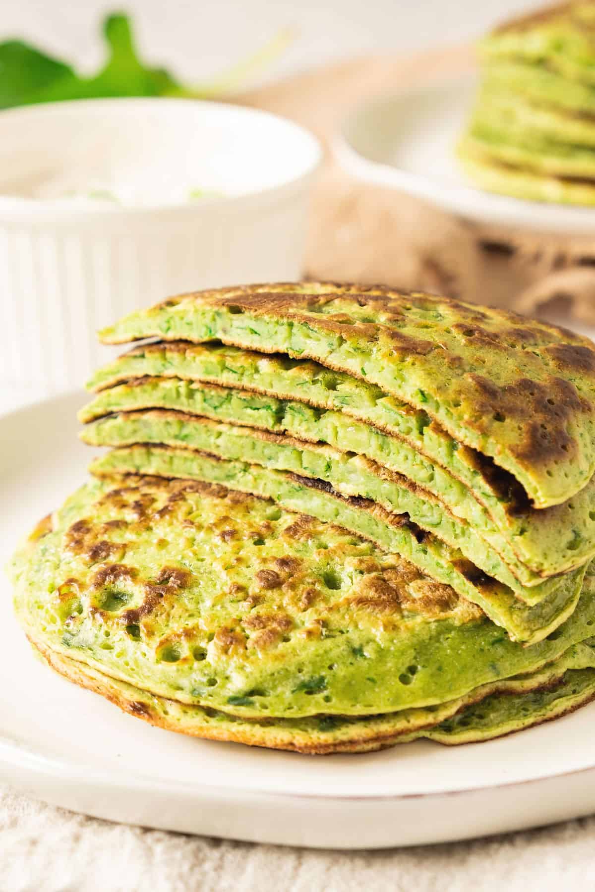 Halved stack of chard pancakes on top of whole ones. White plate.