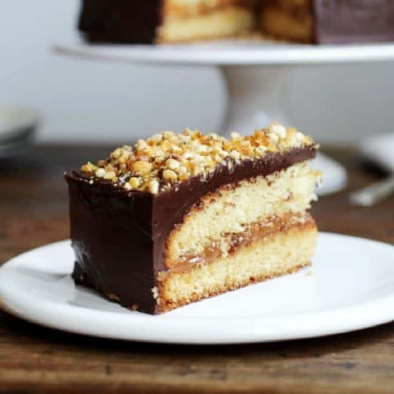 White plate with a slice of dulce de leche birthday cake with chocolate frosting.