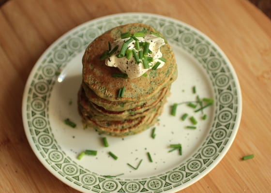 Stack of chard pancakes on white green plate on a wooden board.
