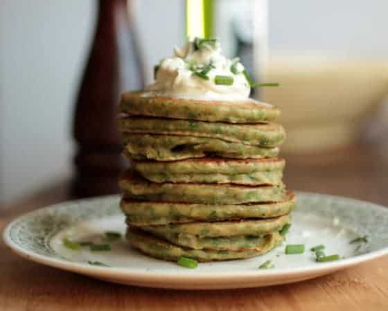 Stack of chard pancakes on a plate, sour cream and chive garnish.