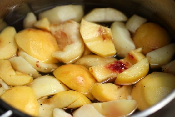 Chunks of peaches with water in large metal saucepan
