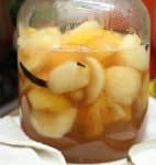 Close up of peaches in syrup inside a large glass jar