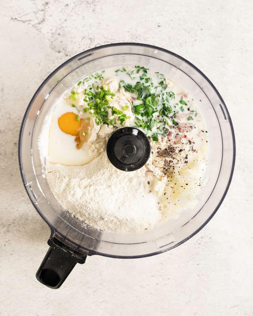 Food processor bowl with ingredients for chard pancakes. Top view. Stone background. 