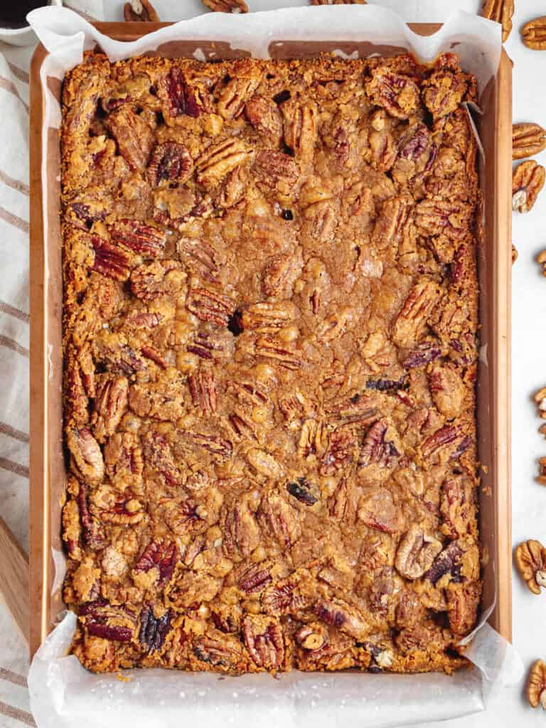 Rectangular copper pan with baked pecan bars. Top view. White background.