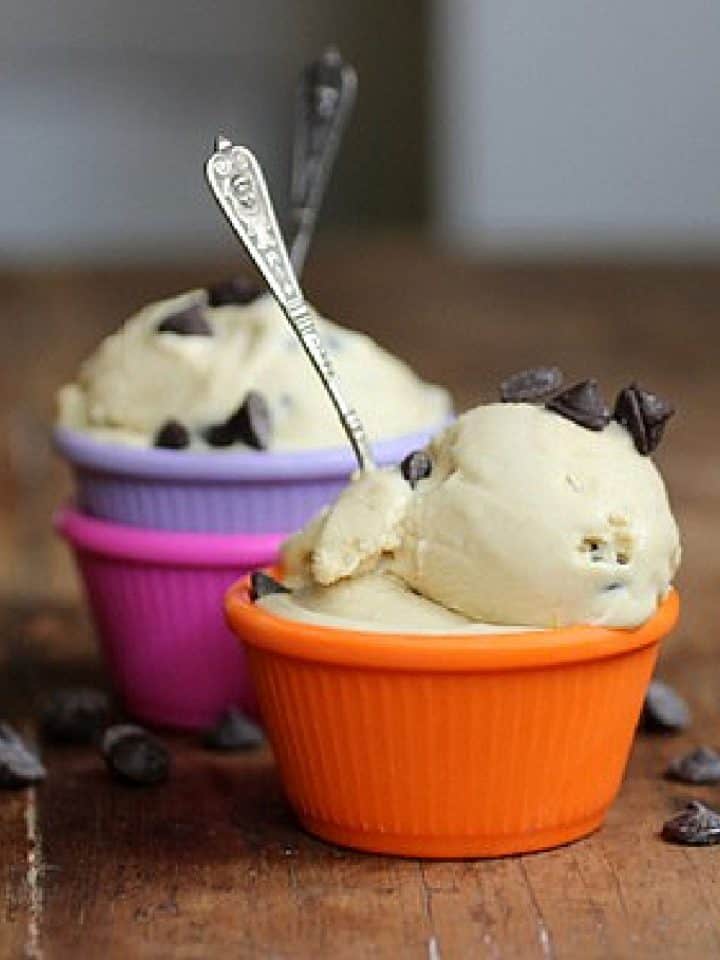 Colorful bowls with chocolate chip cookie ice cream with spoons on a wooden table.