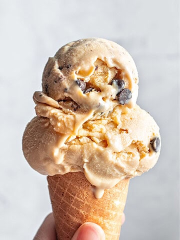 Cone with scoops of chocolate chip cookie ice cream against a light gray background.