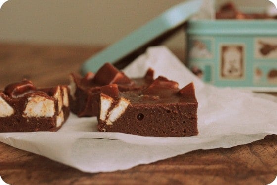 Chocolate marshmallow fudge pieces on a white paper. Wooden table, light blue tin.