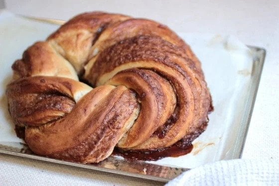 Whole baked cinnamon challah wreath on a metal sheet with parchment paper. 