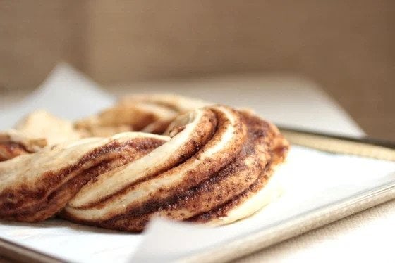 Unbaked view of cinnamon filled challah bread on a cookie sheet with parchment paper.